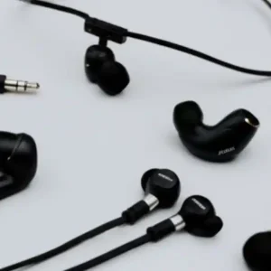 A high-angle, detailed shot of various earbuds, including a pair of classic wired earbuds, a set of wireless earbuds with a connecting neckband, and a sleek, modern true wireless earbud with its charging case, arranged on a neutral background to illustrate the different types of headphone technology.